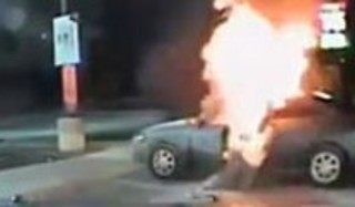 火のついた車に戻る男